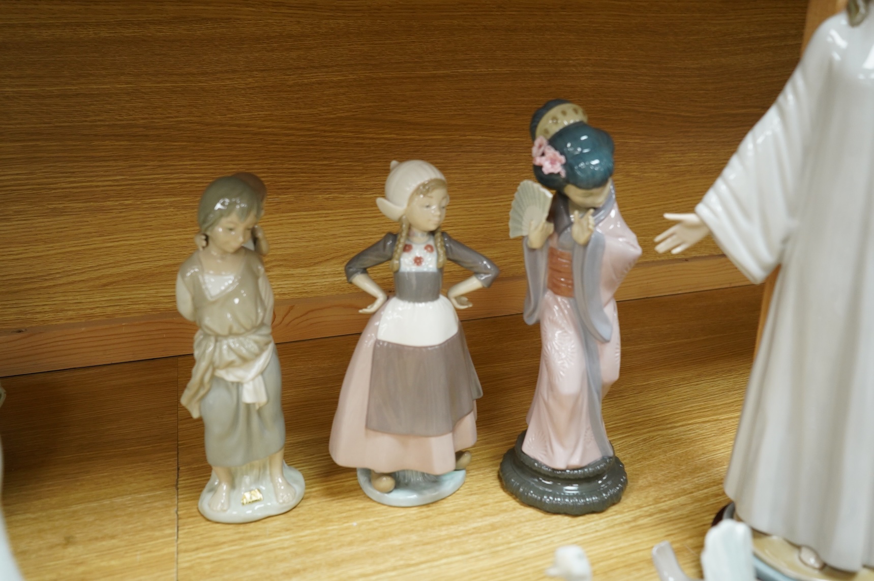 A group of Lladro figurines including: a Japanese Geisha, a model of Christ, 3 birds, various children, an angel bell etc. (all boxed) (13)